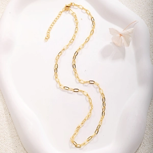 Detail of gold-plated paperclip chain necklace with lobster clasp on a white wavy tray