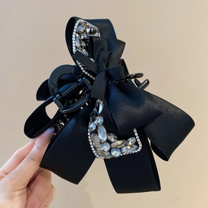 Detailed close-up of a black satin ribbon hair claw clip with sparkling rhinestones