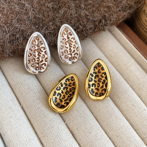 Leaf-shaped leopard print earrings in gold and silver finish on a jewelry box