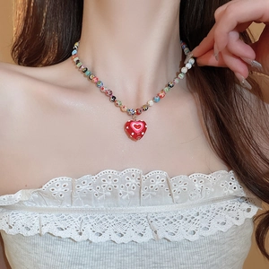 Colorful beaded necklace with a red heart pendant and polka dots on a model