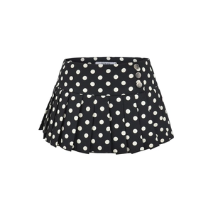 Détail d'une mini-jupe plissée à pois noirs et blancs avec boutons décoratifs argentés