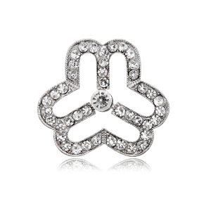 Macro shot of silver clover brooch featuring sparkling white crystals and floral design