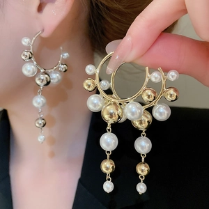 Detailed view of pearl and gold bead tassel C-shaped earrings on model for size and drop length