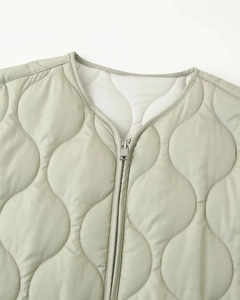 Detail view of wave-quilted jacket featuring crew neck design and metal zipper closure