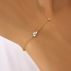 Detailed view of a gold chain bracelet featuring three pear-shaped clear gemstones on a wrist