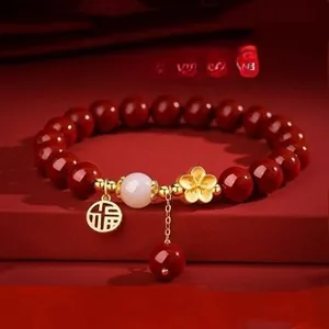 Close-up of a red agate bracelet with a gold blossom charm and lucky Fuh symbol pendant