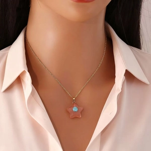 Close-up of a gold star pendant necklace with pink stone on model for daily wear