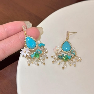 Detail of drop turquoise earrings with white flowers, pearls, and zircon tassels