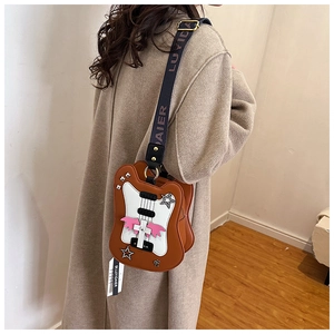 Detail of guitar shaped crossbody bag in brown PU leather with wings and star rivets