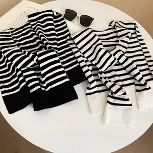 Minimalist knit striped shawl scarves in black and white displayed on a white table