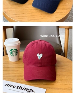 Macro shot of embroidered white heart patch on a claret baseball cap with premium texture