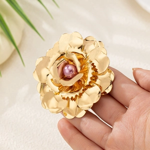 Elegant gold flower brooch with a pink pearl center held in hand for banquet styling