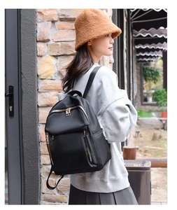 Side view of a large black nylon backpack with gold zippers worn by a model in a casual setting