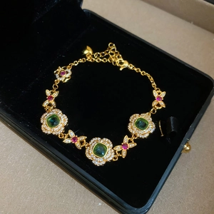 Detail of 24K gold plated bracelet with green gems and flower links in a velvet box