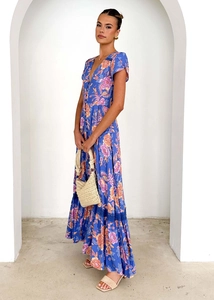 Detail of blue floral maxi dress with V-neck and boho print in a bright architectural setting