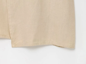 Détail de l'ourlet de la robe midi en lin beige montrant la texture du tissu et couture