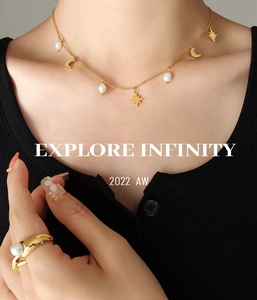 Primer plano de collar dorado con dijes de estrella y luna y perlas en la modelo
