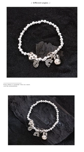 Macro detail of silver beaded bracelet featuring rabbit, heart, and Fu character charms