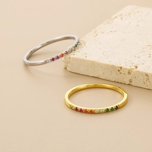 Detail of gold and silver thin rings featuring a rainbow zirconia setting on stone