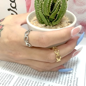 Detail view of gold and silver chain link rings on fingers against a book background