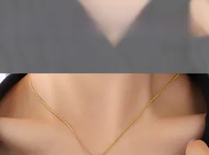 Close-up of a sleek golden snake chain necklace showing a smooth metallic texture on a model