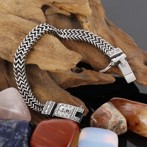 Détail d'un bracelet gourmette double en acier titane avec symbole masculin sur bois brut