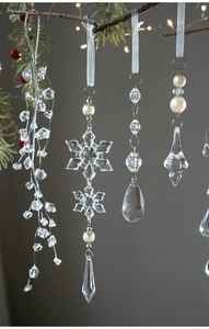 Detail view of crystal Christmas tree ornaments hanging on pine branch with ribbon