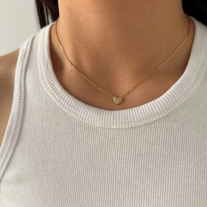 Minimalist gold heart necklace with micro-pave zirconia for women on a model closeup