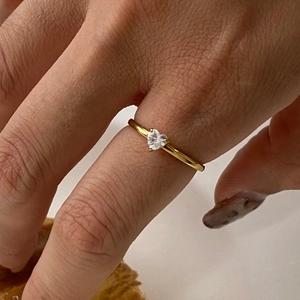 Macro view of gold heart-shaped zircon ring worn on finger showing fine craftsmanship