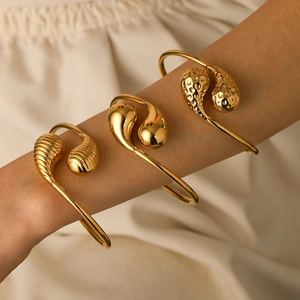Three gold teardrop stainless steel open bracelets with smooth, hammered and threaded textures