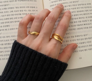 Detail of minimalist 925 sterling silver wavy rings worn on hand over an open book