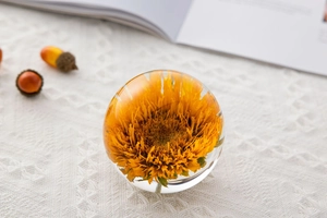 Close-up of yellow dried flower inside glass crystal ball on white lace tablecloth