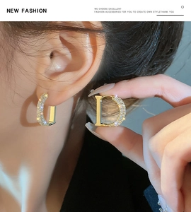 Macro detail of gold letter D earrings with sparkling pave zircon settings