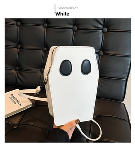 Detailed view of a white coffin-shaped ghost crossbody bag on a black leather sofa