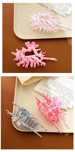 Close-up of three oversized shell-shaped hair claws in pink, blue, and white with spots