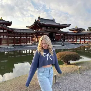 Navy blue cropped knit sweater featuring a prominent white bow pattern and long sleeves