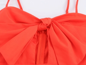 Close-up of a red vacation dress featuring a large front bow and thin shoulder straps