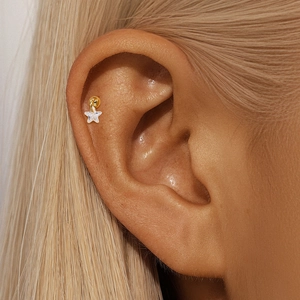 Detailed close-up of a golden star cartilage earring with crystals worn by a model