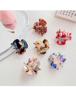 Close-up of six assorted acetic acid hair claws with marble patterns on white leather