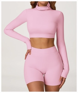 Détail d'un ensemble de yoga rose brossé avec haut court à manches longues et short moulant