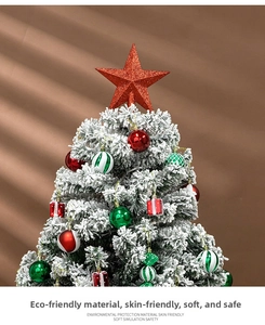 Close-up of snow-flocked Christmas tree with red glitter star topper and colorful ornaments