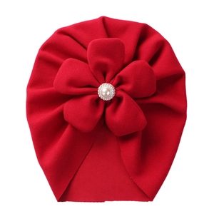 Detailed view of red toddler turban hat featuring a large fabric flower with pearl center