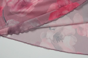 Close-up of semi-transparent mesh fabric with purple floral print and lettuce edge hem