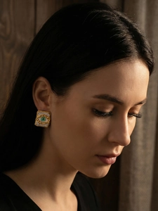 Close-up of square evil eye stud earrings with green center and pavé crystals on model