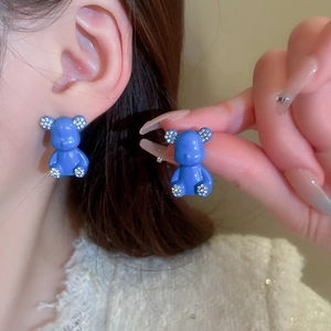 Detailed macro view of vibrant blue resin bear earrings with white rhinestone accents