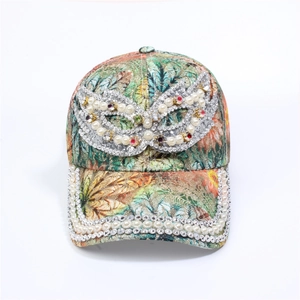 Detailed close-up of floral baseball cap with pearls, rhinestones and silver mask emblem
