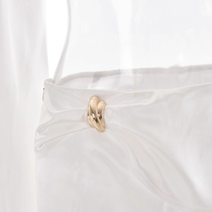 Détail de la jupe en satin blanc avec boucle en métal doré et texture de soie lisse