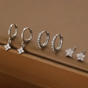 Detailed set of silver zircon earrings with star, moon and flower charms in a jewelry box
