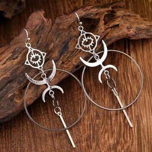 Bohemian silver geometric earrings with crescent and eye charms on rustic wood backdrop