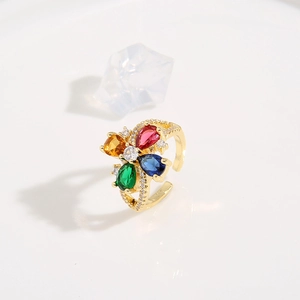 Dettaglio macro di un anello regolabile dorato con fiore a quattro petali e gemme vivaci